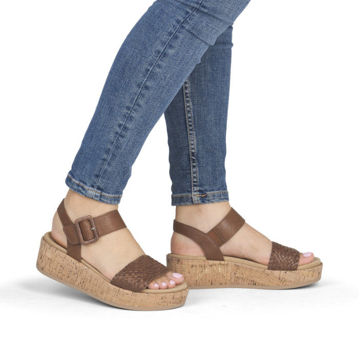 Brown sandals with cork platforms worn with rolled-up blue jeans.