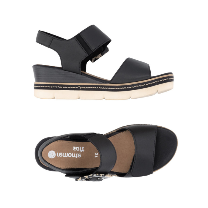 Pair of Black backstrap platform sandals with oversized decorative buckle, two Velcro straps, tan Remonte logo'd footbed, a faux wood grain wedge midsole and  an off-white outsole.