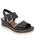 Black backstrap platform sandal with oversized decorative buckle, two Velcro straps, tan Remonte logo'd footbed, a faux wood grain wedge midsole and  an off-white outsole.