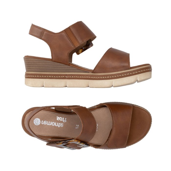 Pair of Brown backstrap platform sandals with oversized decorative buckle, two Velcro straps, Remonte logo'd footbed, a faux wood grain wedge midsole and  an off-white outsole.