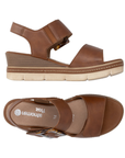 Pair of Brown backstrap platform sandals with oversized decorative buckle, two Velcro straps, Remonte logo'd footbed, a faux wood grain wedge midsole and  an off-white outsole.