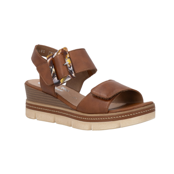 Brown backstrap platform sandal with oversized decorative buckle, two Velcro straps, Remonte logo'd footbed, a faux wood grain wedge midsole and  an off-white outsole.