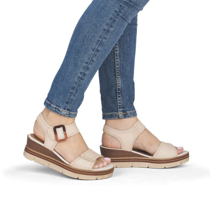Beige wedge sandals worn with blue jeans.