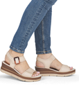 Beige wedge sandals worn with blue jeans.