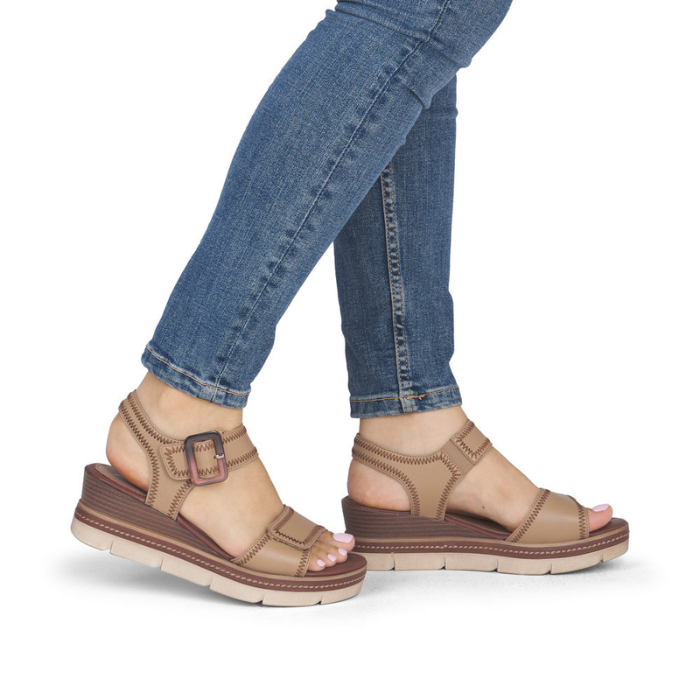Brown wedge sandals worn with blue jeans.