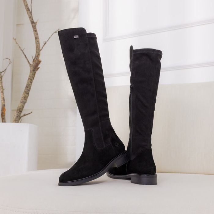 Black knee-high boots on a white surface with a minimal background