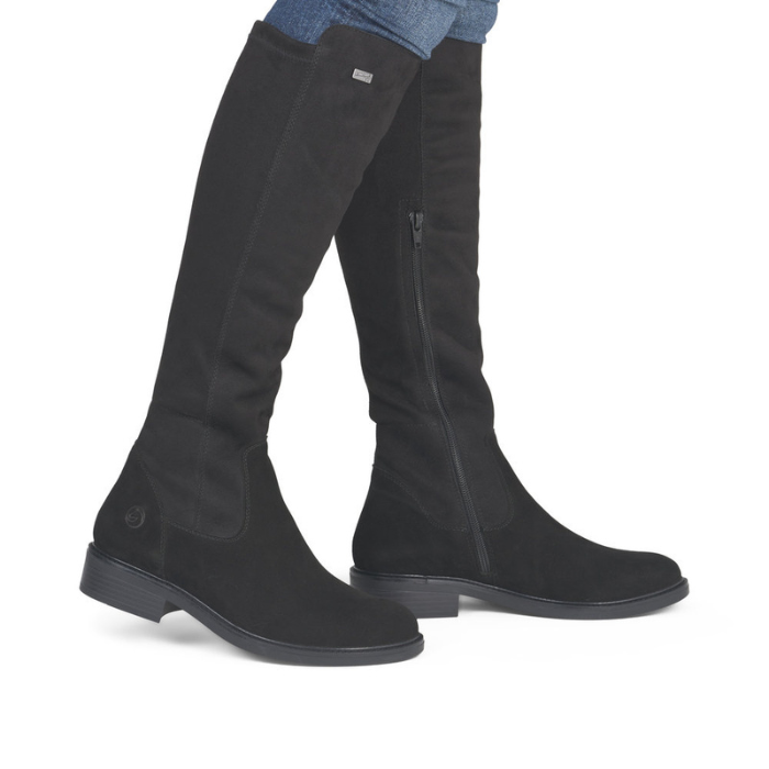 Black knee-high boots worn with blue jeans.