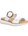 White slide sandal with two Velcro straps, marbled circle buckle, tan Remonte logo'd footbed, and a white platform with beige accents.