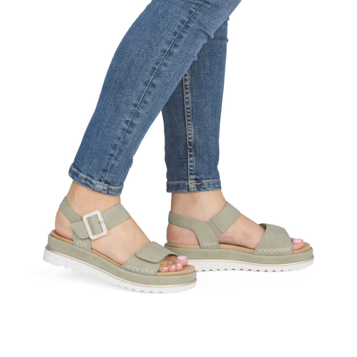 Green backstrap sandals with buckle detail worn with blue jeans.