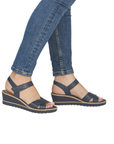 Navy wedge backstrap sandals worn with blue jeans.