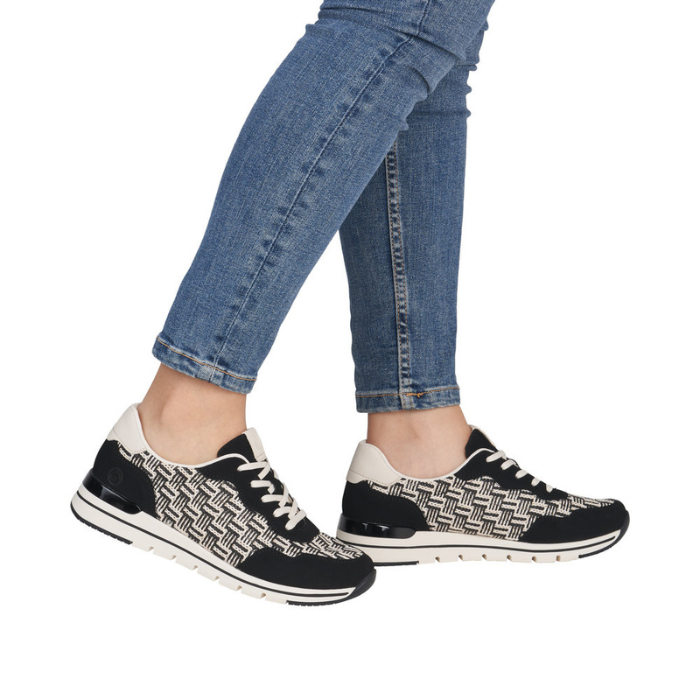 Black and white patterned sneakers worn with blue jeans.