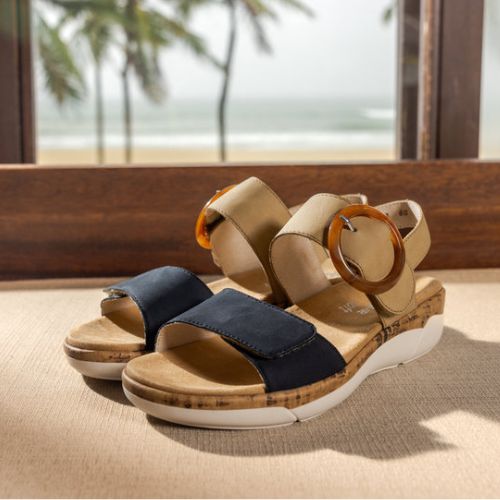 Backstrap Sandals in tan and navy displayed in a tropical cottage scene.