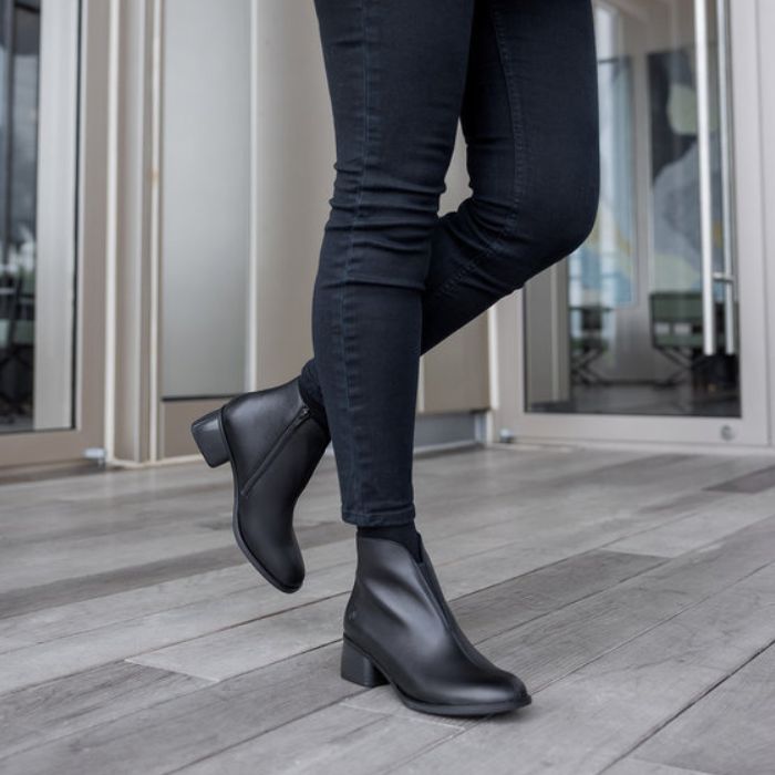 Legs in jeans wearing black leather ankle boot with block heel.