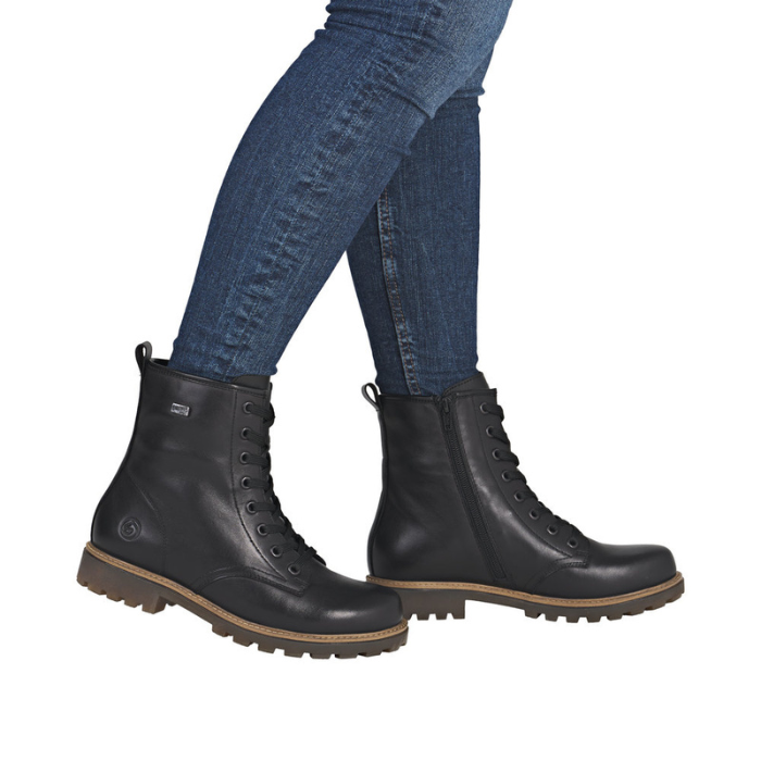 Black leather combat boots worn with blue jeans.