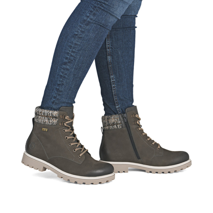 Gray winter boots with patterned cuffs worn with blue jeans.