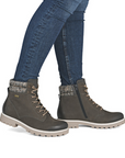 Gray winter boots with patterned cuffs worn with blue jeans.