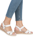 White sandals with faux cork midsole worn with blue jeans.