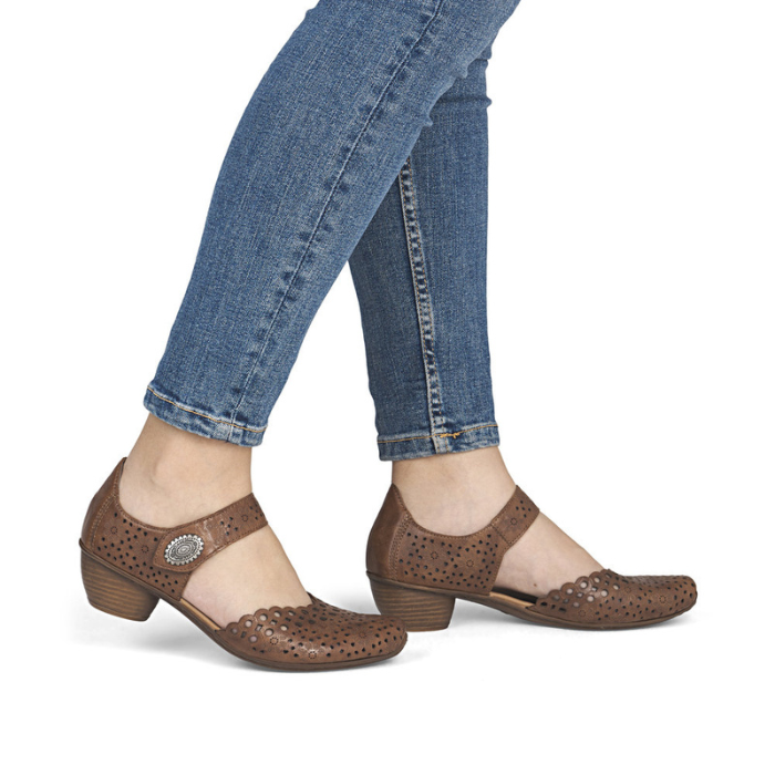 Brown perforated leather Mary-Jane heels worn with jeans.