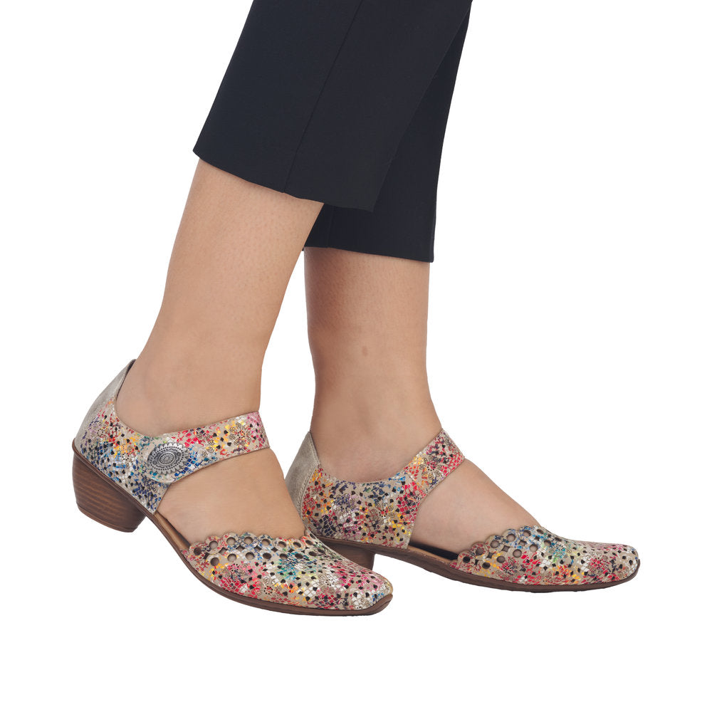 Multicolored floral-patterned perforated Mary-Jane heels worn with black pants.