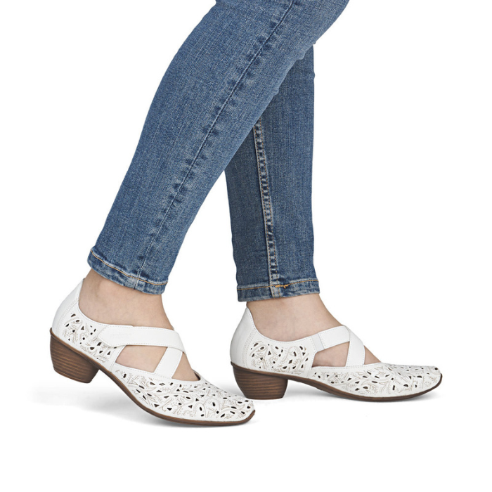 White perforated heeled Mary Janes worn with blue jeans.