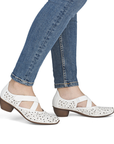 White perforated heeled Mary Janes worn with blue jeans.