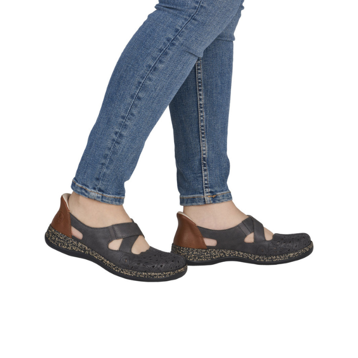 Person wearing blue jeans and grey perforated Mary Janes.