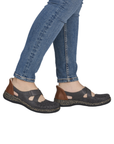 Person wearing blue jeans and grey perforated Mary Janes.