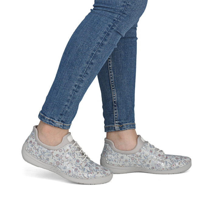 Gray floral sneakers worn with blue jeans.