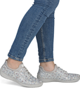 Gray floral sneakers worn with blue jeans.