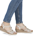 Gold strappy wedge sandals worn with blue jeans.
