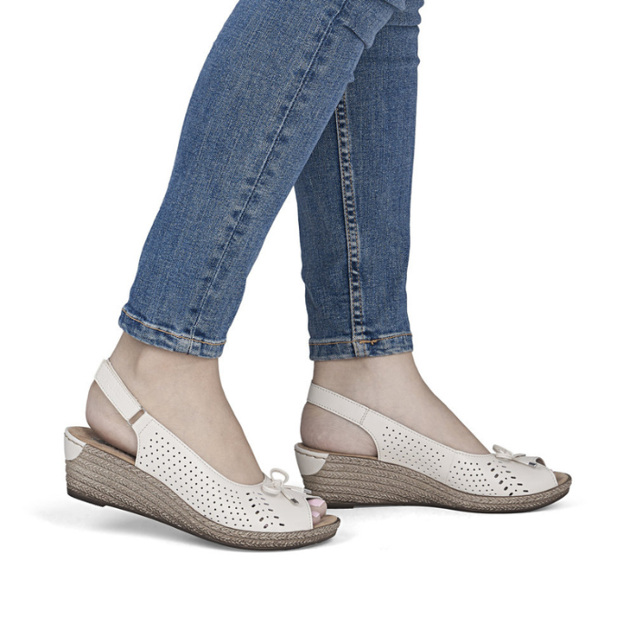 White wedge peep toe sandals worn with blue jeans.
