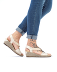 Gold wedge sandals worn with blue jeans.