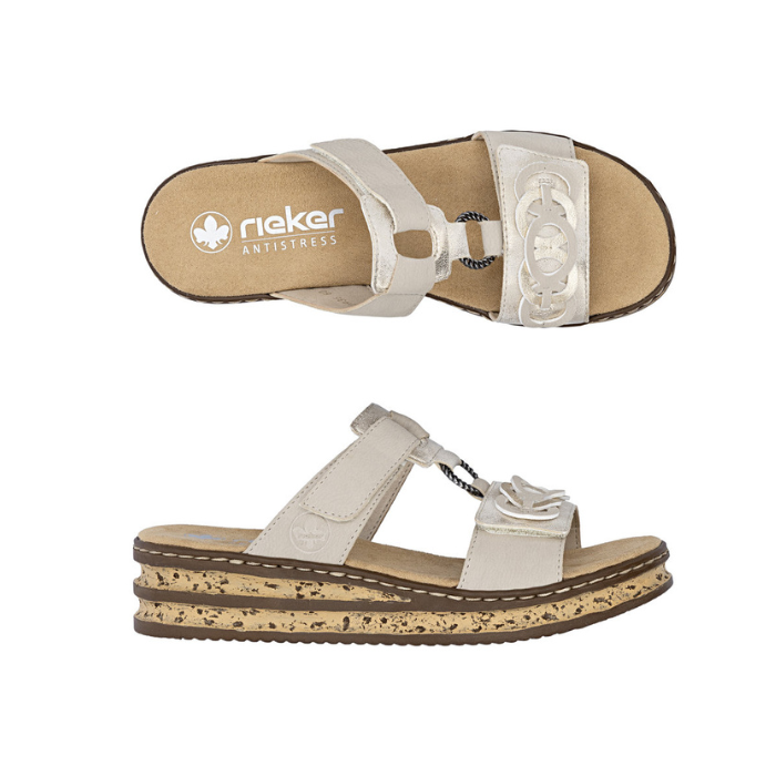 Pair of beige slide sandals with decorative embellishments, faux cork midsole, and tan Rieker logo'd footbed.