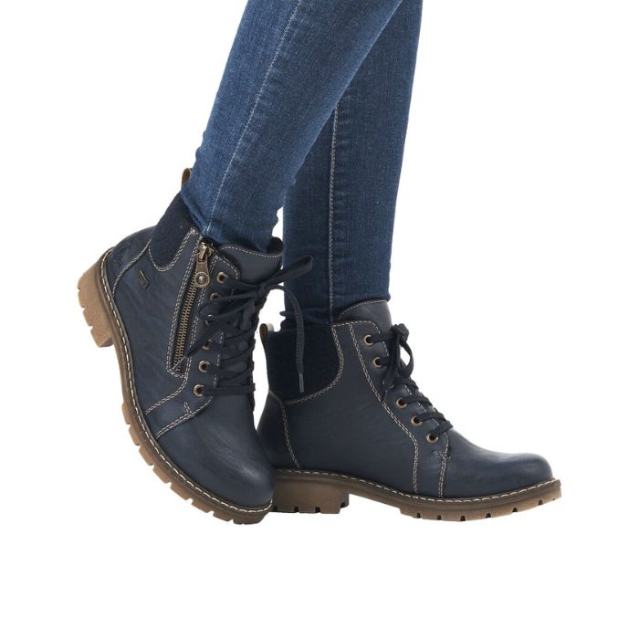 A women in jeans wearing Rieker Navy lace up ankle boots with brown outsole. 