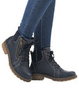 A women in jeans wearing Rieker Navy lace up ankle boots with brown outsole. 