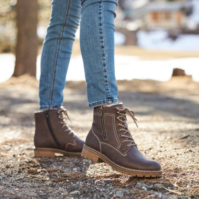 Women in jeans wearing brown lace up ankle boot.