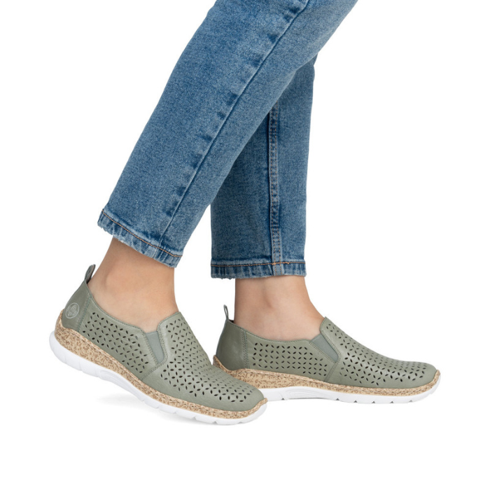 Green perforated slip on shoes worn with blue jeans.