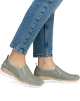 Green perforated slip on shoes worn with blue jeans.