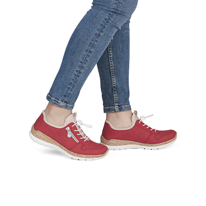 Red slip-on sneakers with white outsoles worn with blue jeans.