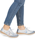 White sneakers with blue accents worn with blue jeans.