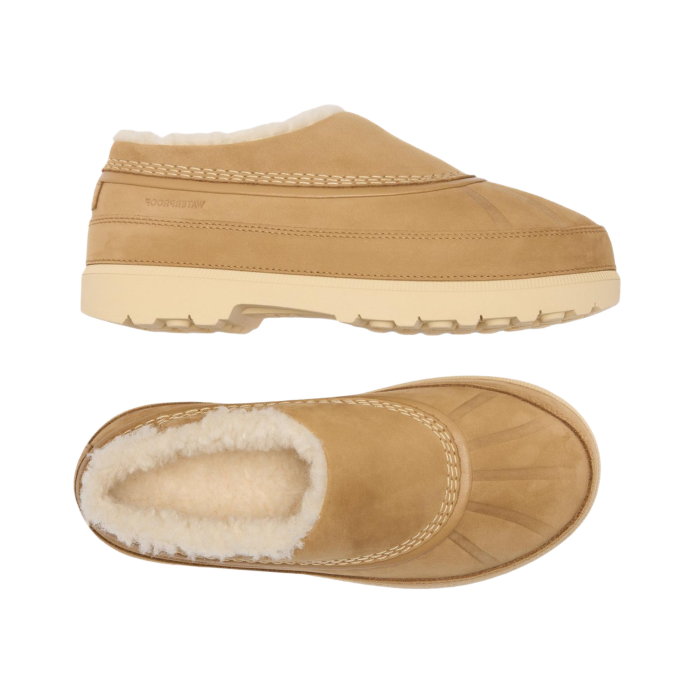 Pair of tan slip-on clog-style shoes with a cream-colored faux shearling lining and a thick cream outsole.