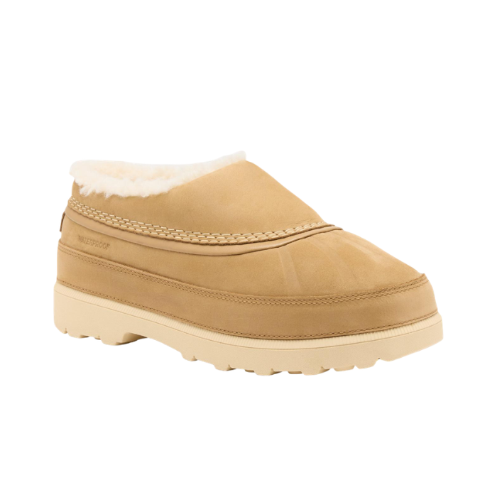 A tan slip-on clog-style shoe with a cream-colored faux shearling lining and a thick cream outsole.