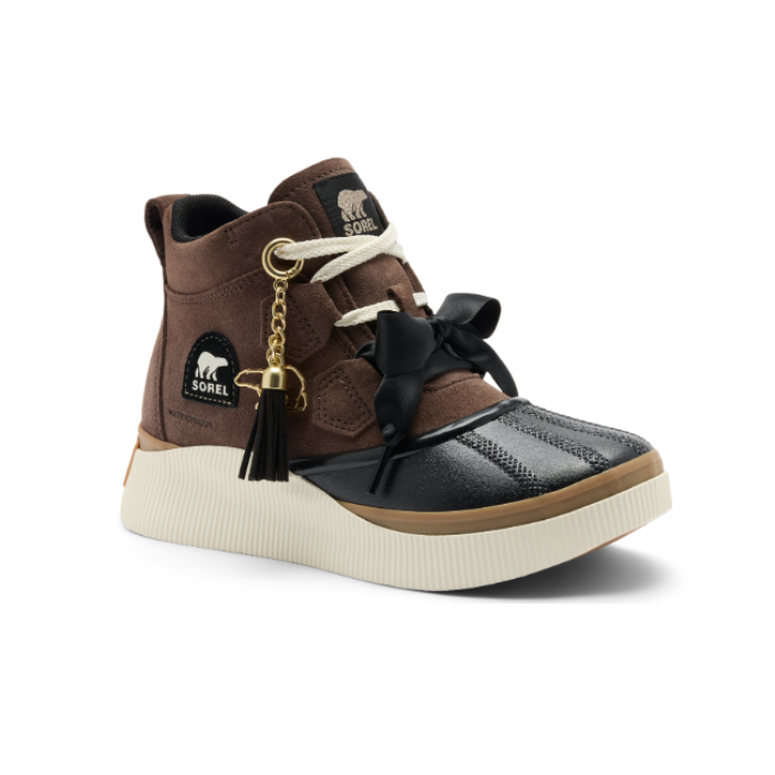 A brown suede platform duck boot with a black rubber toe cap, cream platform midsole, white laces, a black bow on vamp, and a gold tassel polar bear charm.