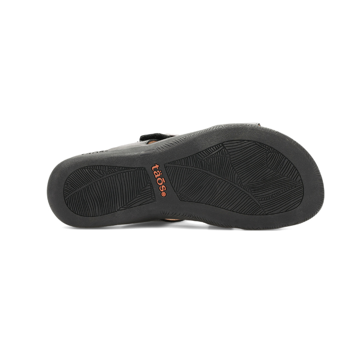 Black rubber outsole with leaf pattern tread and orange Taos logo stamped in middle.