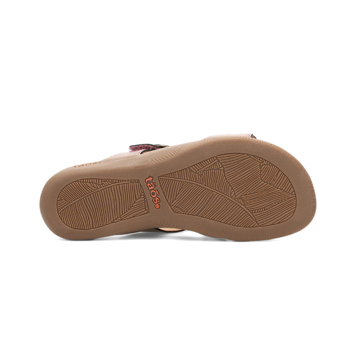 Beige rubber outsole with leaf pattern tread and orange Taos logo stamped in middle.