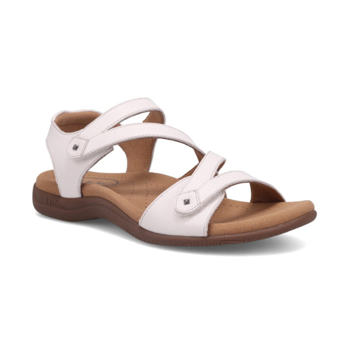 White backstrap sandal with two Velcro cross straps, tan Taos logo'd footbed and dark brown outsole.