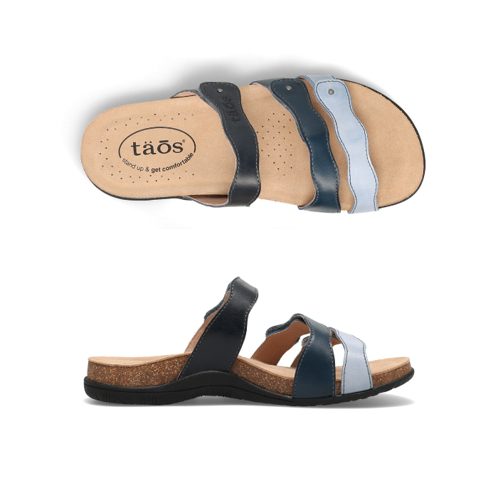 Pair of Slide sandals with wavy straps; black strap, dark blue strap and light blue strap, tan Taos logo'd footbed and black outsole.