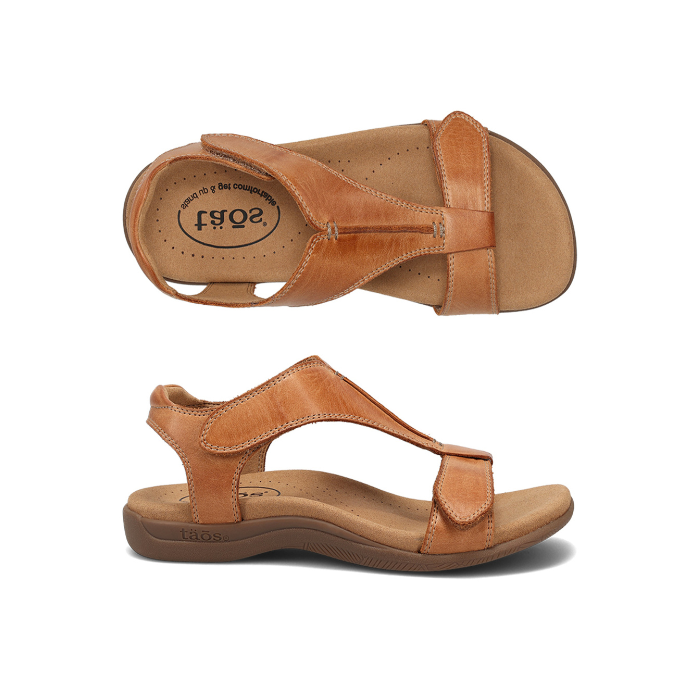 Pair of Backstrap leather sandals in tan with two adjustable Velcro straps, t-strap design, tan Taos logo'd footbed and brown rubber outsole.