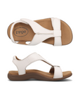 Pair of Backstrap leather sandals in white with two adjustable Velcro straps, t-strap design, tan Taos logo'd footbed and brown rubber outsole.