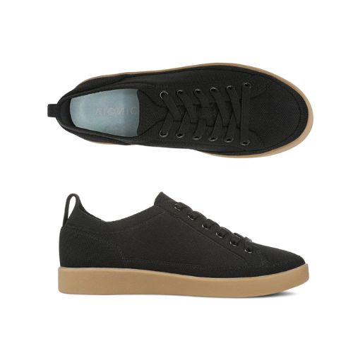 Pair of black knit sneakers with black elastic laces, blue Vionic logo'd footbed and thick tan outsole.